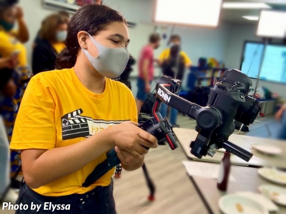 Young girl filming with camera in school